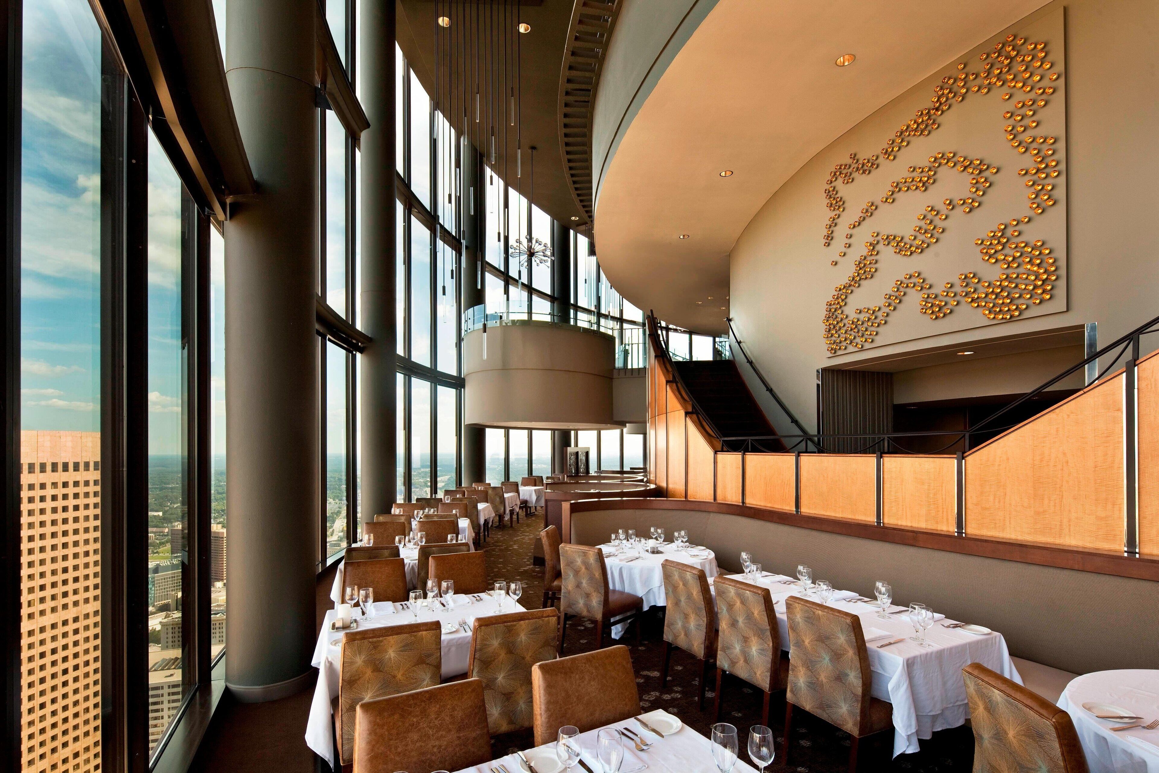 Un ristorante di un grattacielo con viste panoramiche sulla città, ampie finestre e un design d'interni moderno.