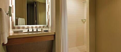 Un baño moderno con tocador, espejo y zona de ducha.