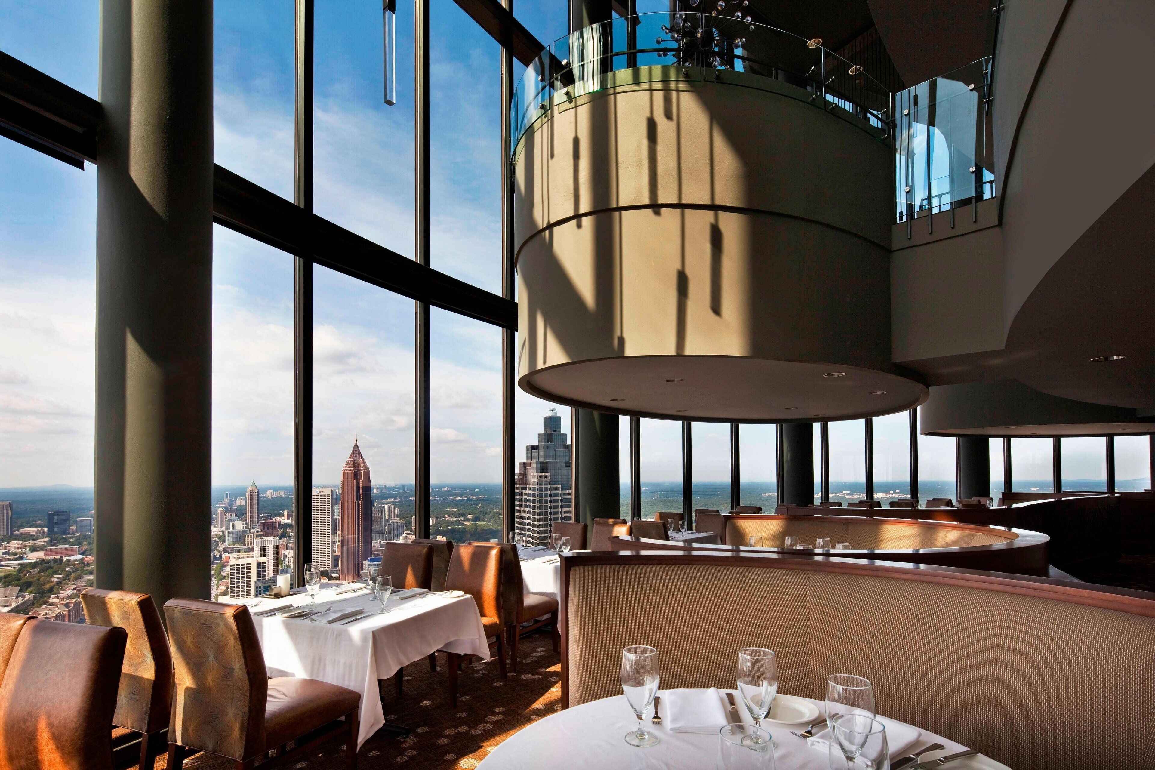 A high-rise restaurant with panoramic city views, large windows, and modern interior design.