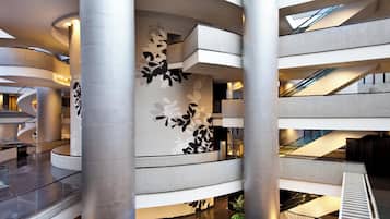 A multi-level atrium with curved columns, a central staircase, and a decorative wall with leaf patterns.