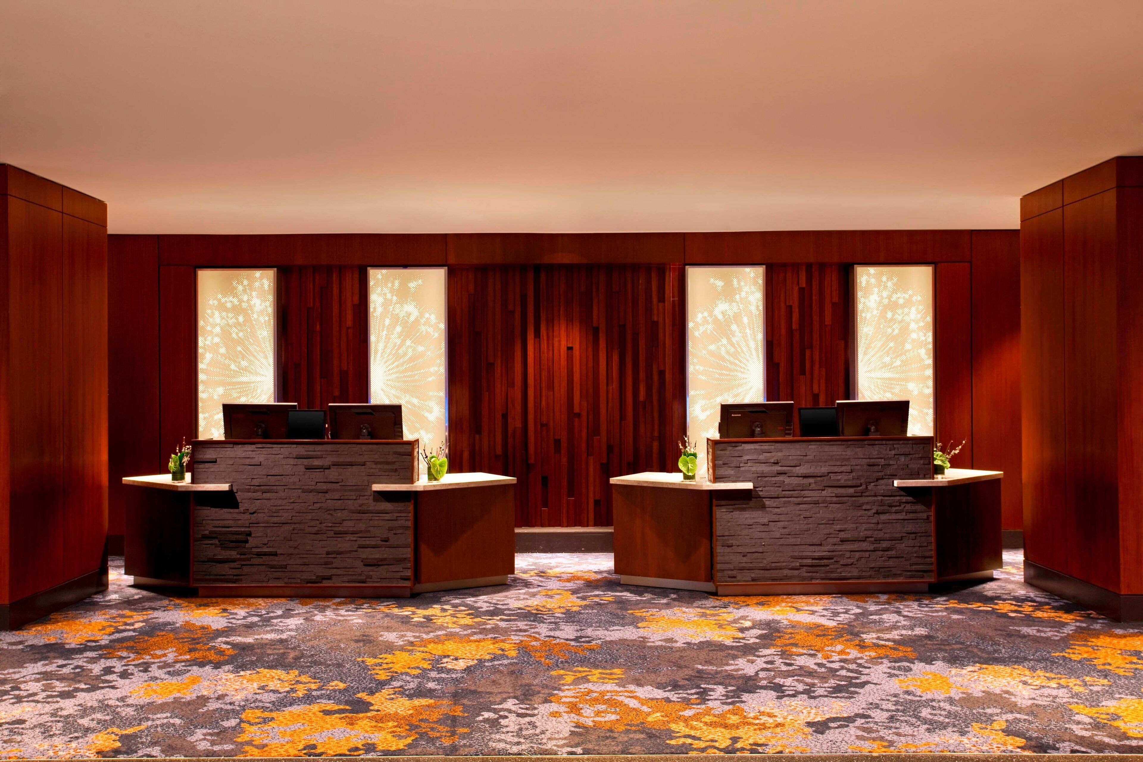 A reception area with two reception desks, a patterned carpet, and wooden paneling.