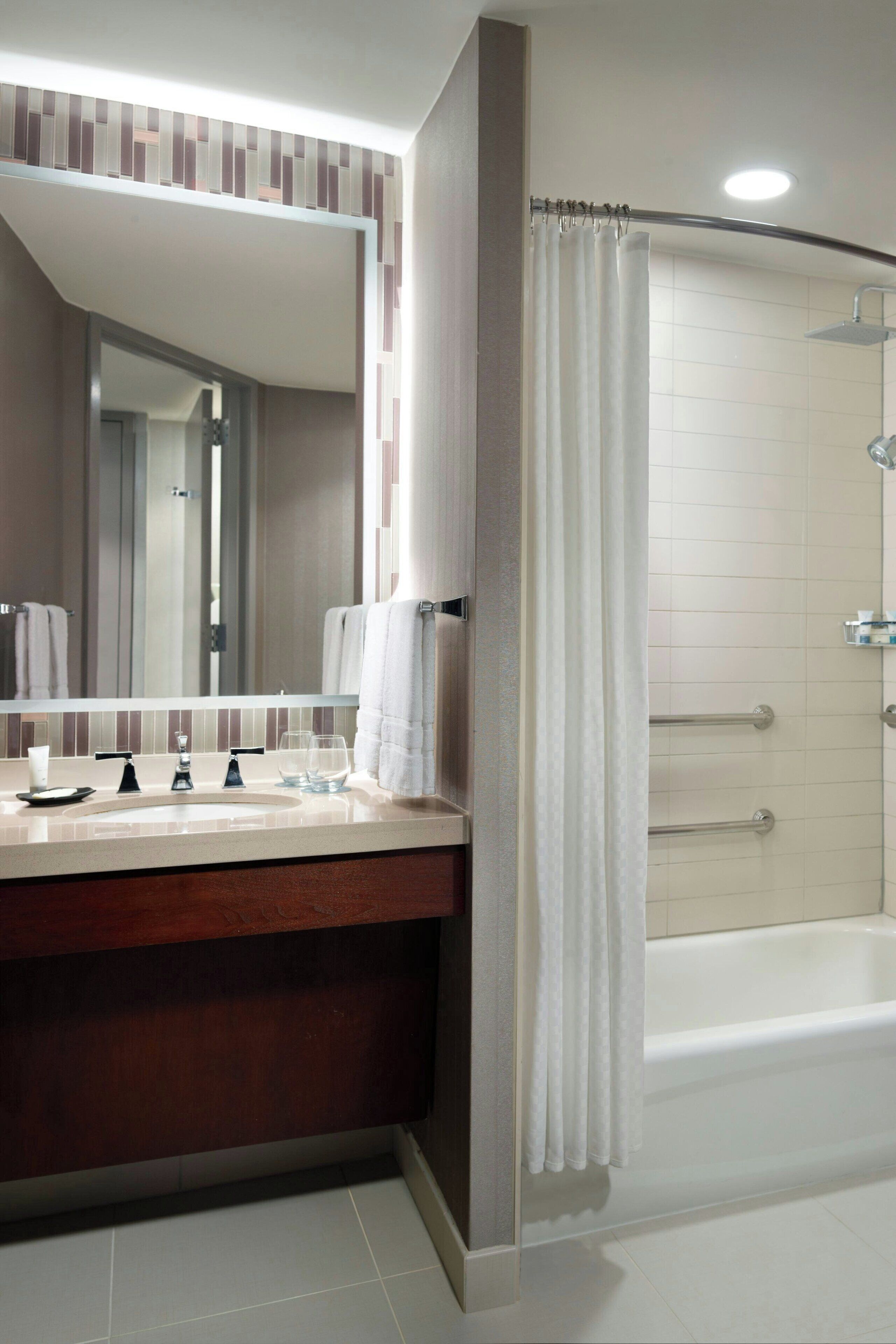 A modern bathroom with a vanity, mirror, and shower.