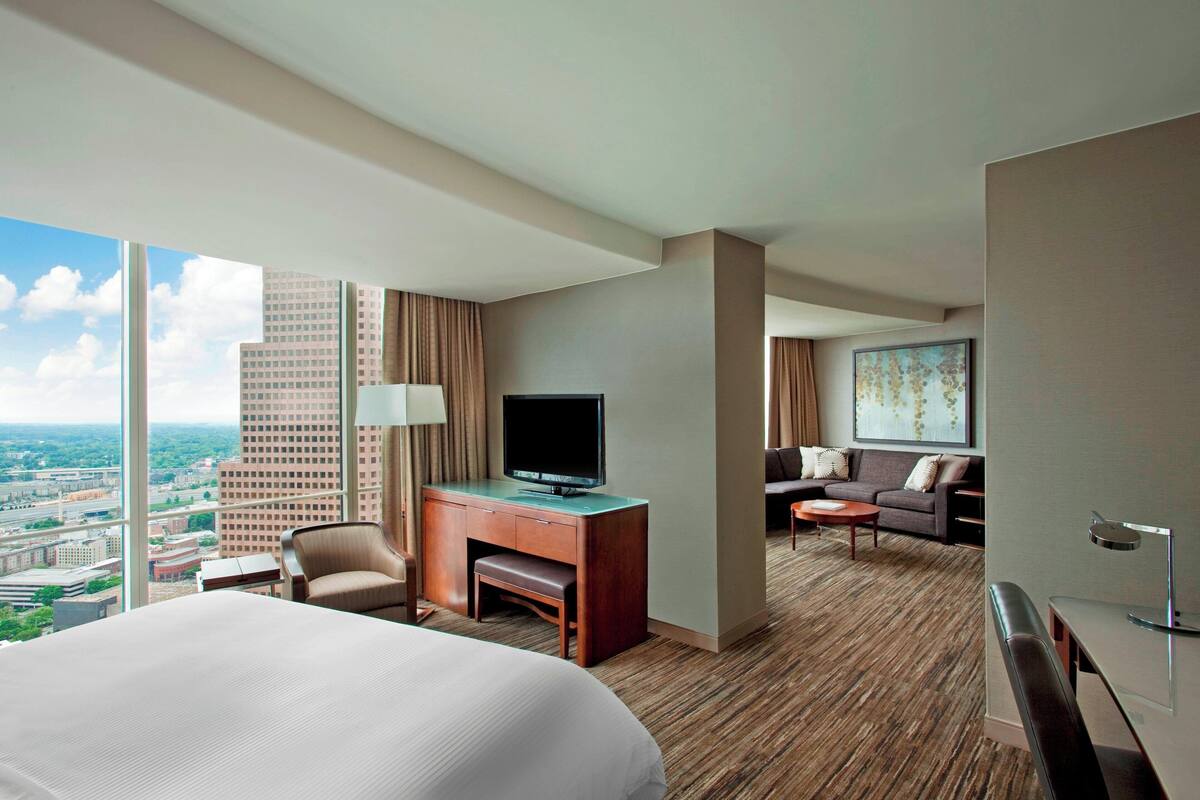 Hotelkamer met een groot bed, een bureau met een televisie, een bank en uitzicht op de stad.