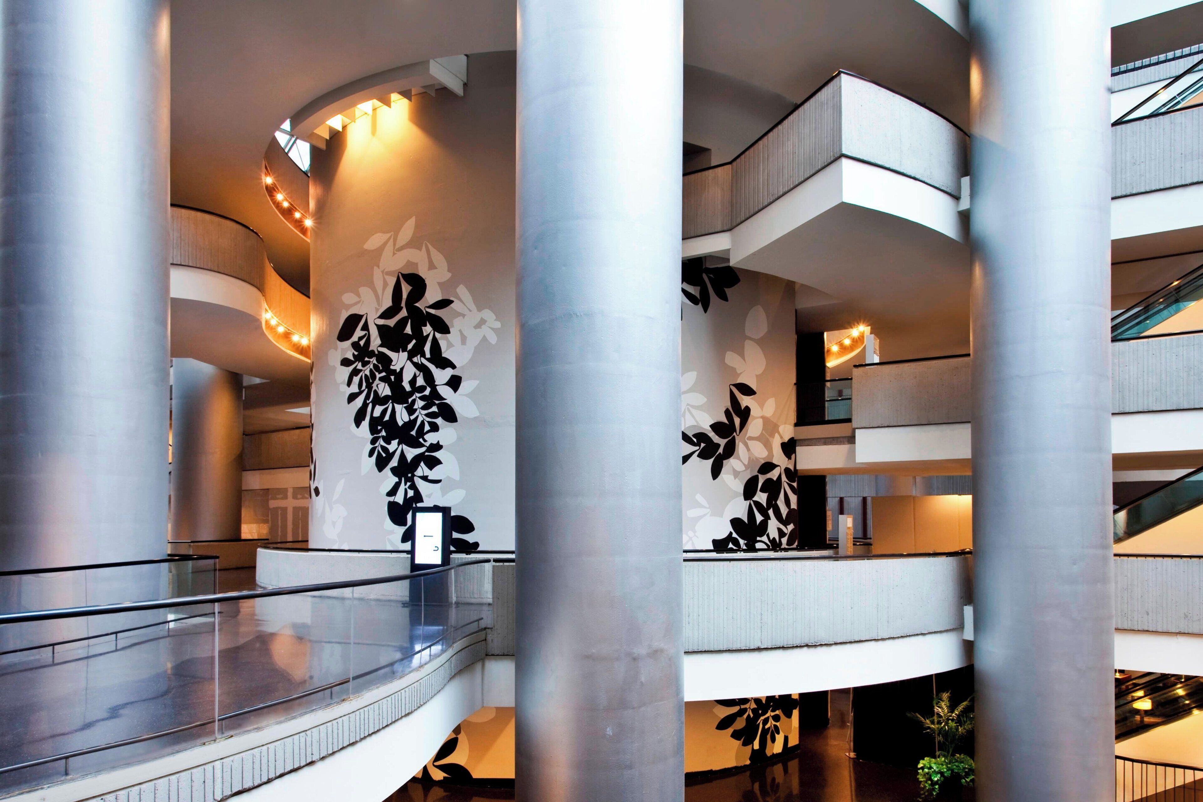 A multi-level atrium with a central column, glass railings, and a modern architectural design.
