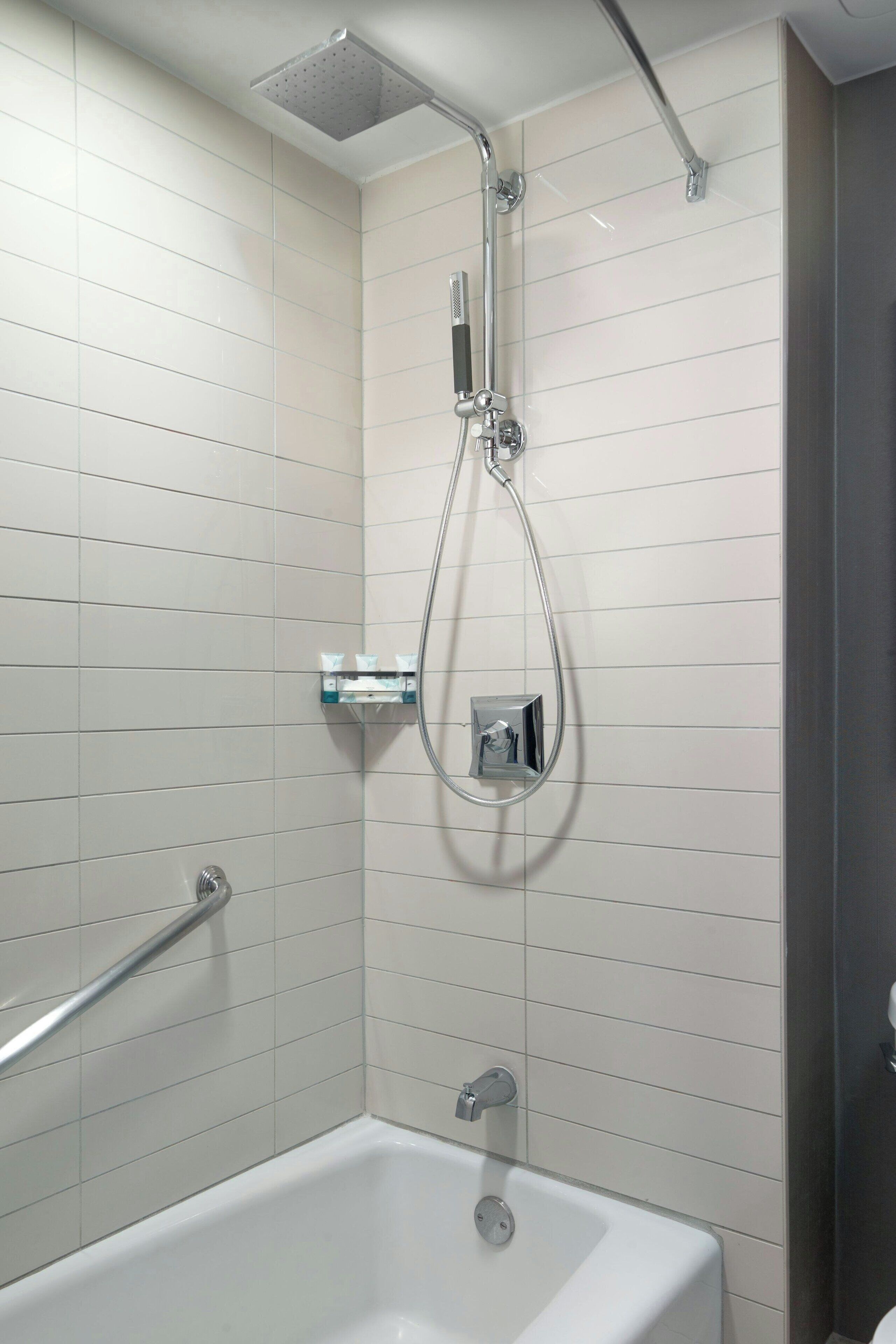 Un baño moderno con una bañera, una ducha y un cabezal de ducha manual, además de otro cabezal de ducha manual en la pared.