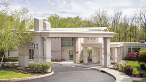 Un edificio moderno con un acceso cubierto, un balcón y un jardín bien cuidado.