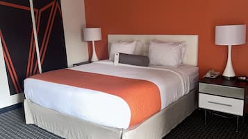 Une chambre d’hôtel comprenant un lit, deux tables de chevet avec des lampes, un téléphone et un mur orné d’un motif géométrique.