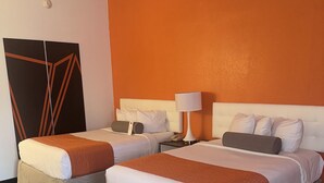 Habitación de hotel con dos camas, un espejo grande, una mesita de noche y un reloj de pared.