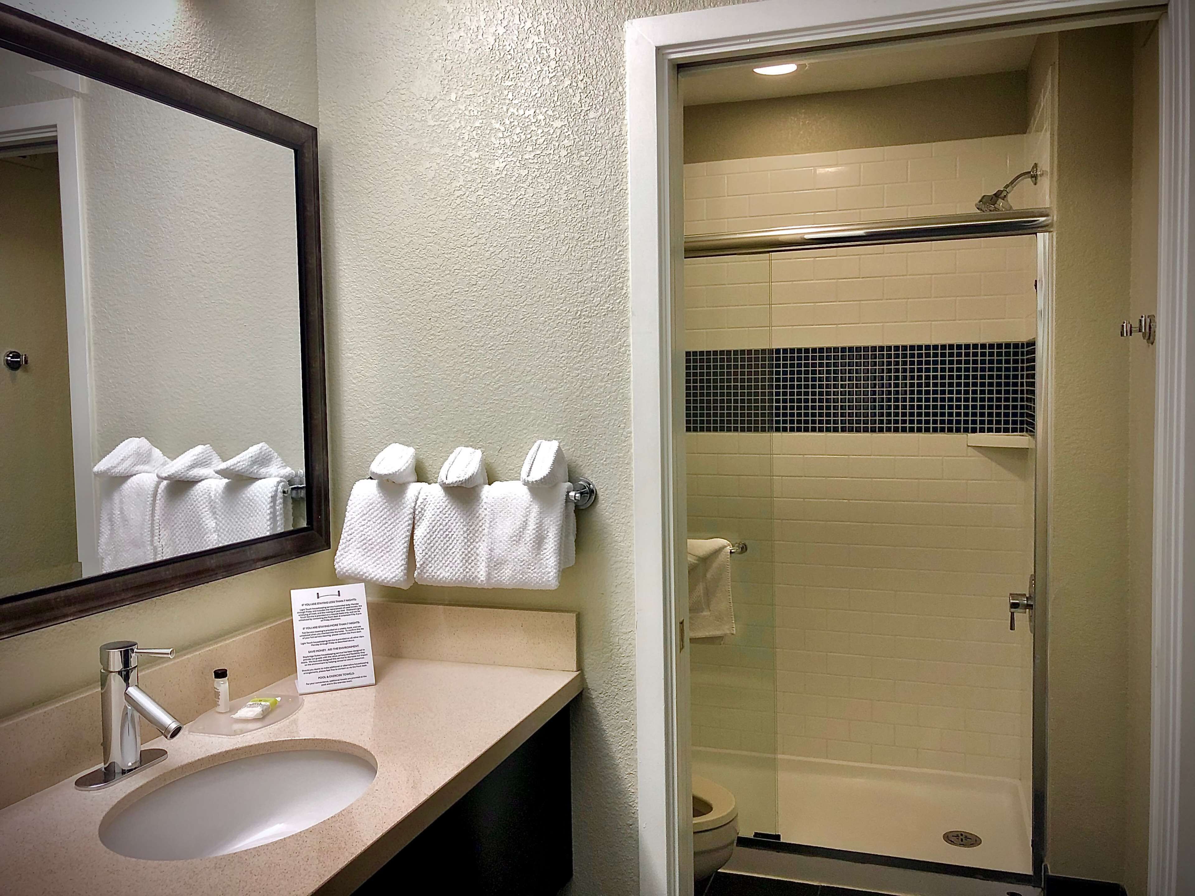 A bathroom with a sink, mirror, and a glass-enclosed shower.