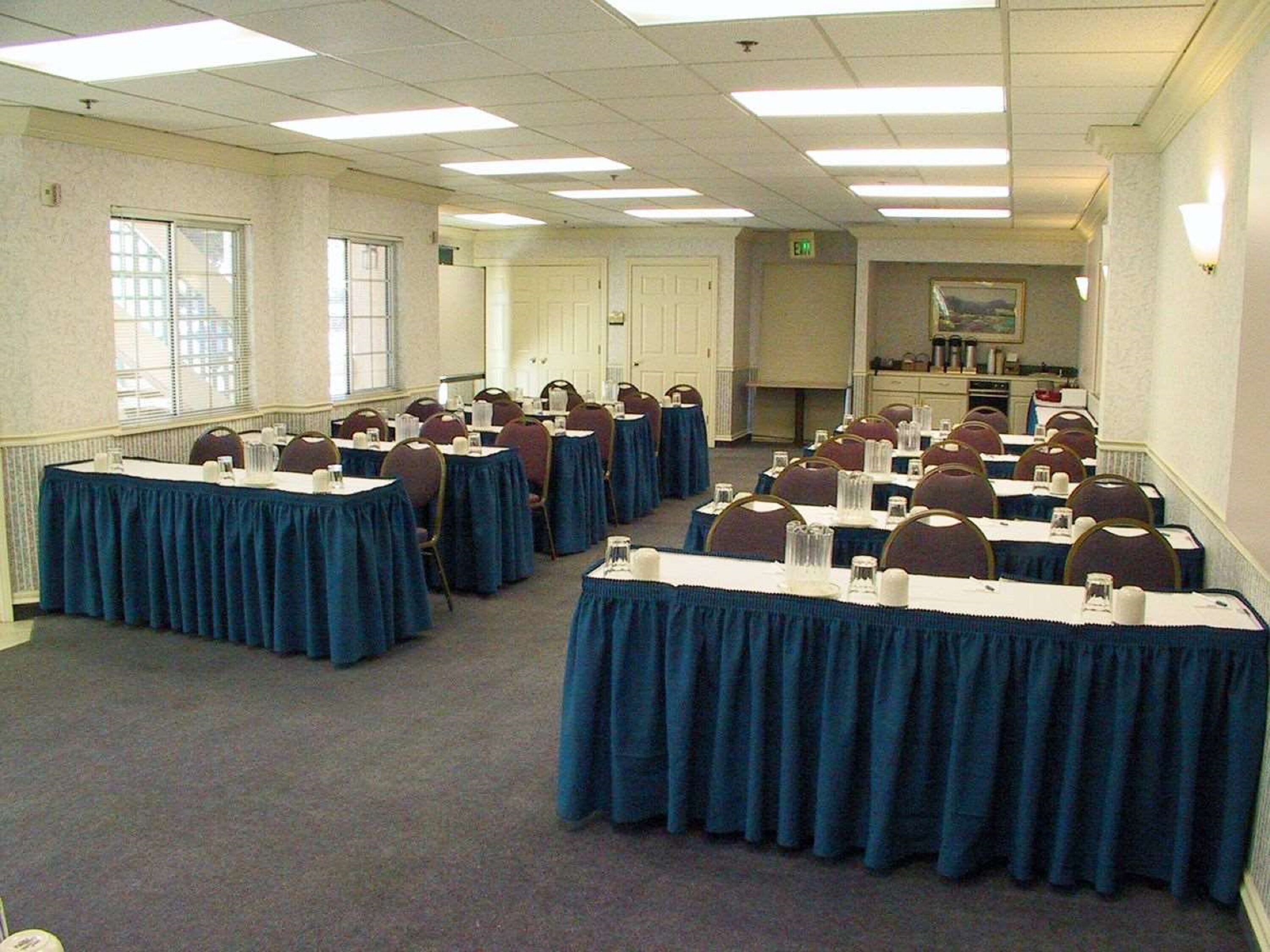 A conference room with rows of tables, chairs, and a large window.