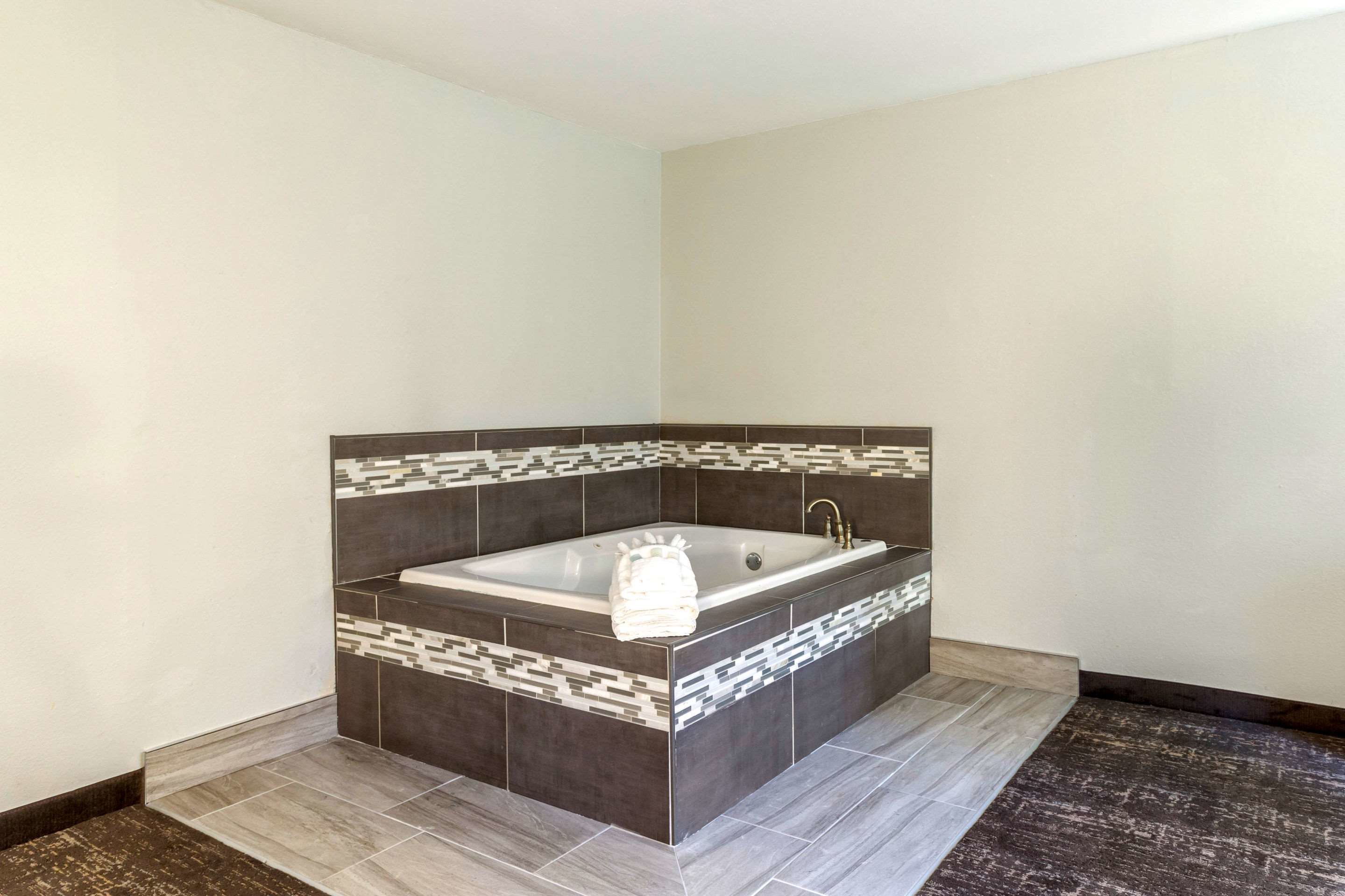 A modern bathroom with a freestanding bathtub, tiled walls, and a dark floor.