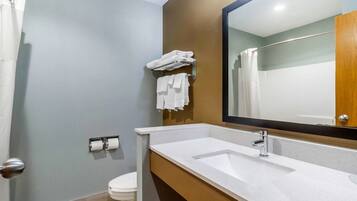 Un baño con lavamanos, espejo y barra para toallas.