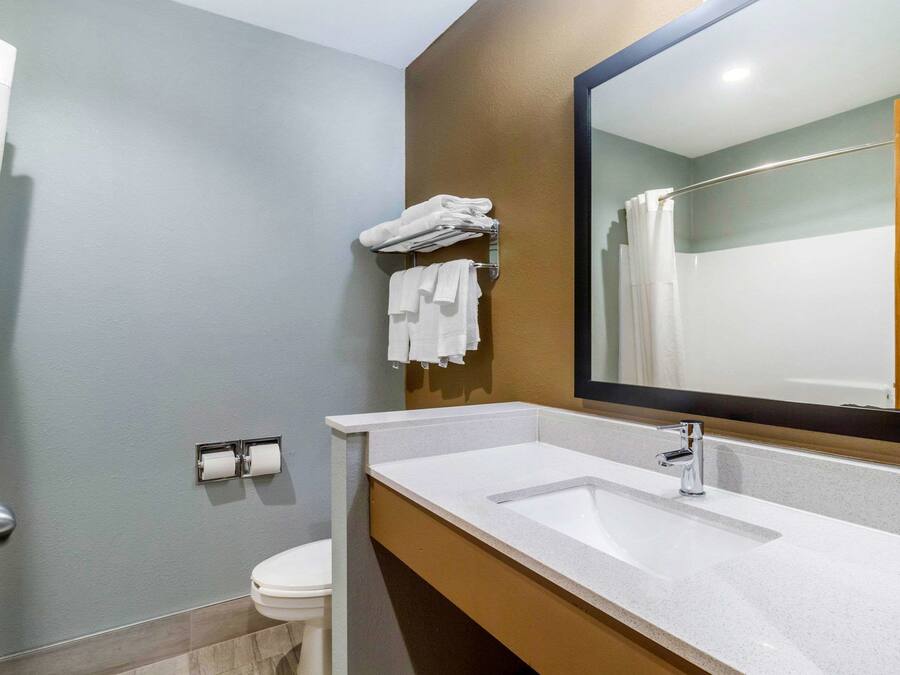 Un baño con lavamanos, espejo y barra para toallas.