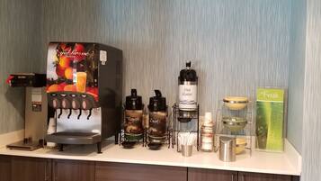 A coffee station with a branded coffee machine, multiple dispensers, and a fresh juice dispenser.