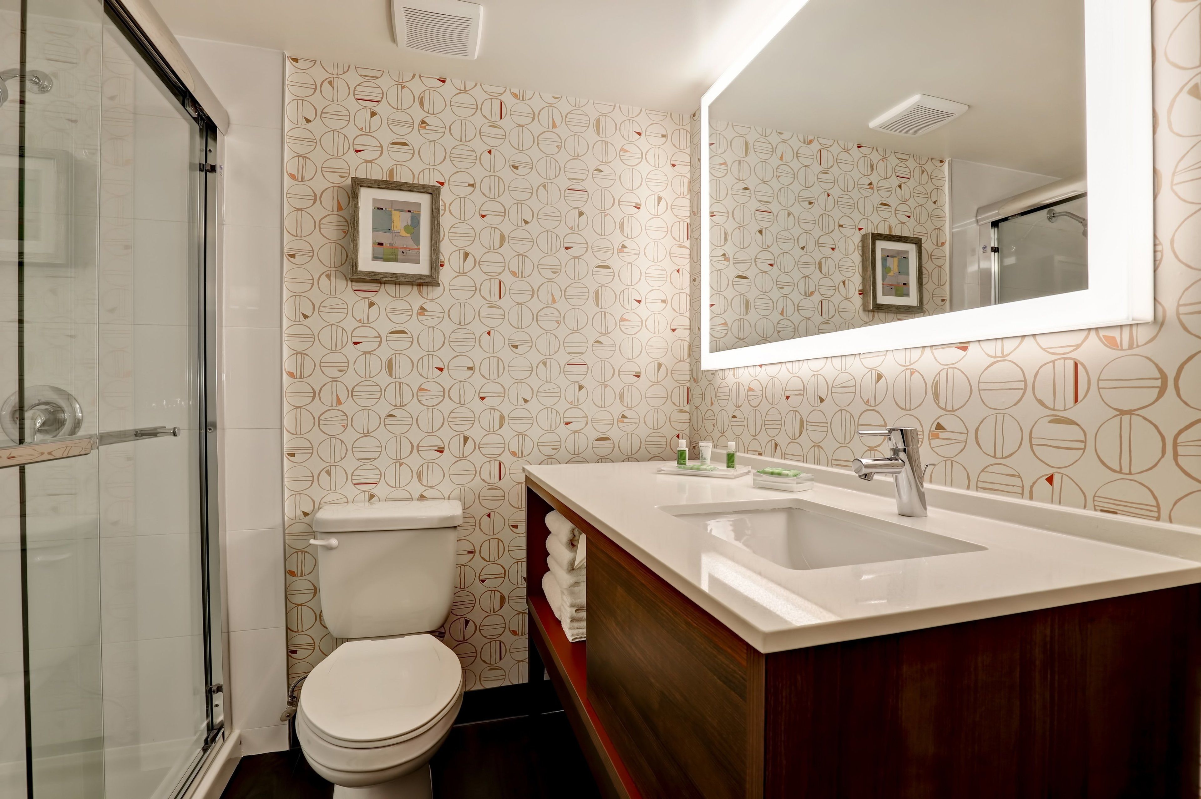 A bathroom with a toilet, a sink, a mirror, and a shower.
