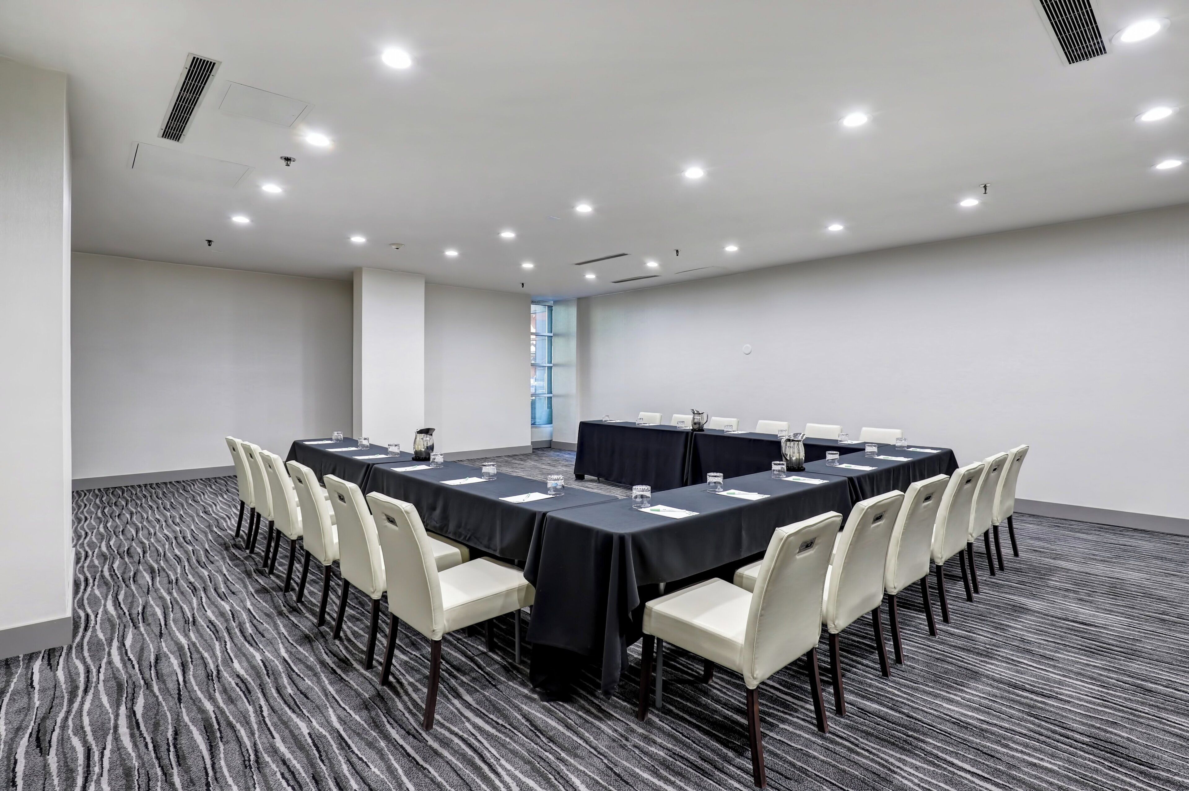 Un salón de conferencias con una mesa larga, sillas y piso alfombrado.