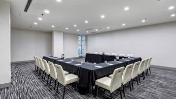Un salón de conferencias con una mesa larga, sillas y piso alfombrado.