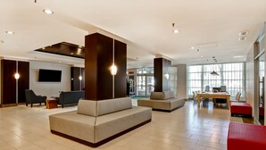 Un hall amplio con asientos modernos, un televisor de pantalla plana y una zona de comedor.