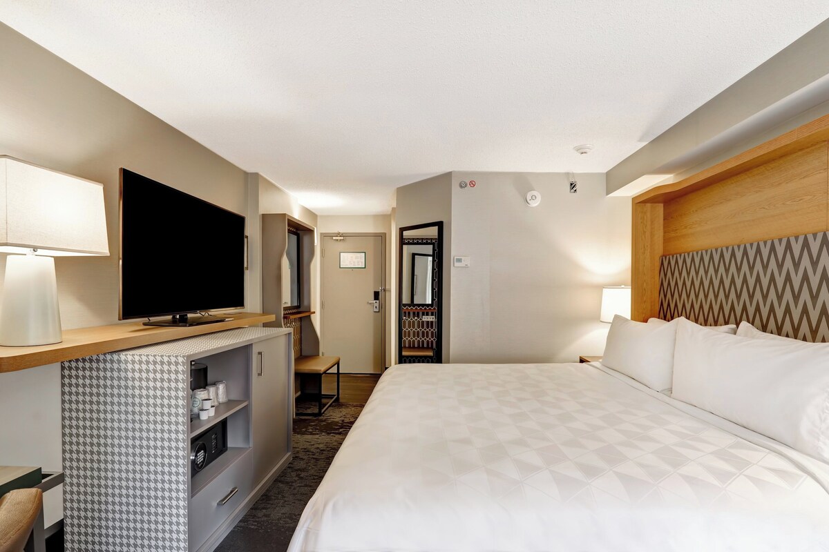 A hotel room with a bed, a TV, a desk, and a wardrobe.