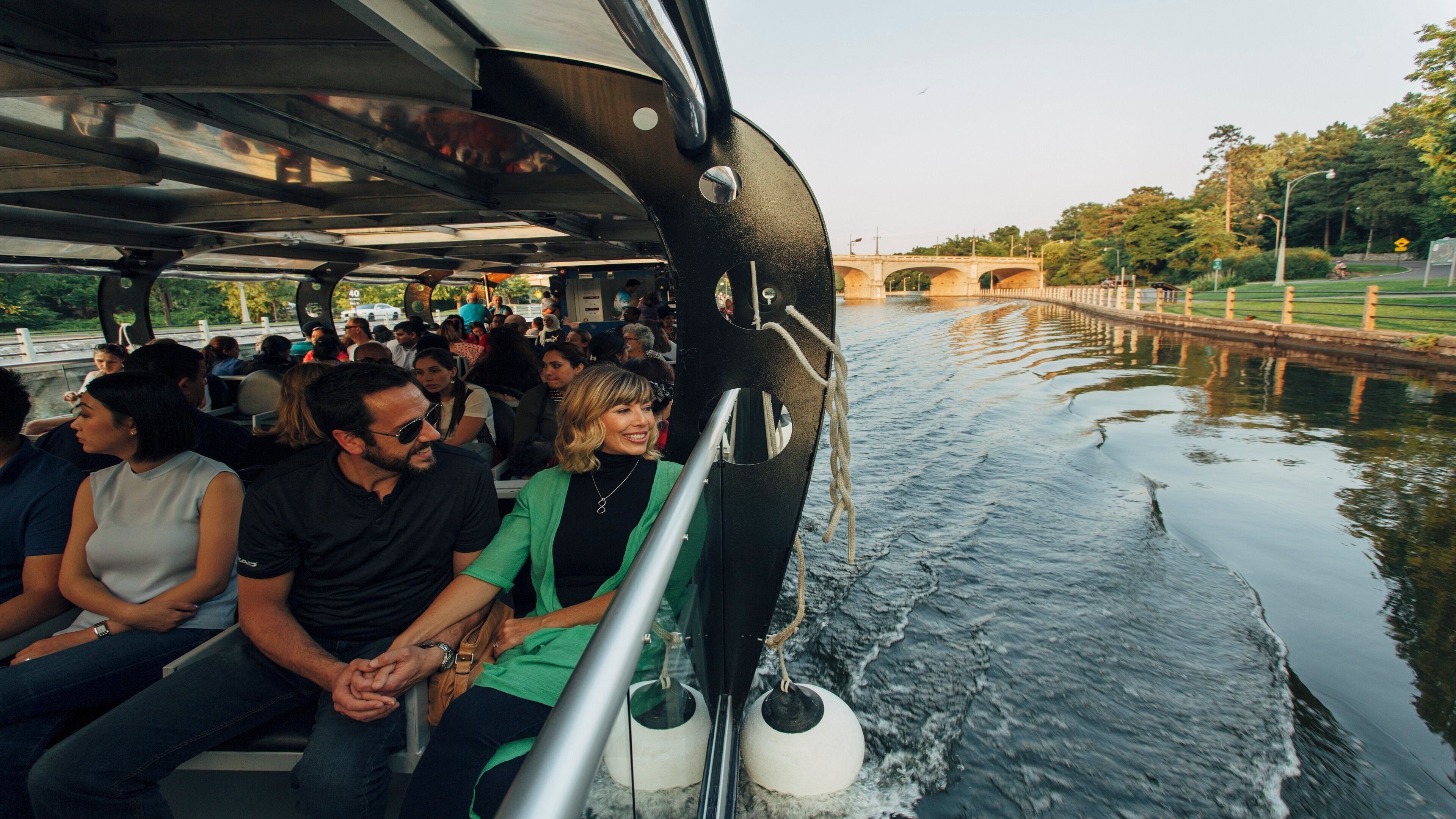 Un bateau transportant des passagers, un pont en arrière-plan et une eau calme.