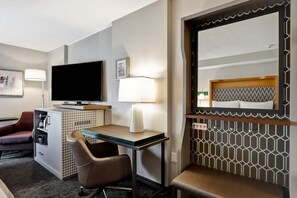 A hotel room with a flat-screen TV, a desk with a lamp, a chair, a sofa, and a bed with a headboard. - Holiday Inn Ottawa Dwtn - Parliament Hill by IHG (Ottawa)