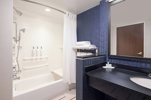 Une salle de bain moderne avec une baignoire, un meuble-lavabo avec un miroir et un espace douche.