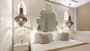 A modern hotel room with a large bed, decorative wall panels, and hanging lamps.