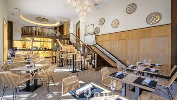 A modern restaurant with a bar area, wooden furniture, and a staircase leading to an upper level.