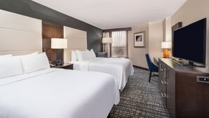 A hotel room with two beds, a desk with a television, a chair, and a window with curtains. - Crowne Plaza Annapolis by IHG (Annapolis)