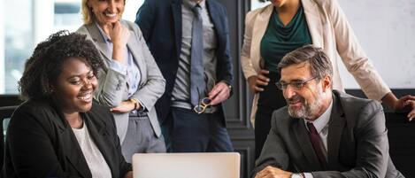 Un grupo de personas en una sala de reuniones con una computadora portátil sobre la mesa.