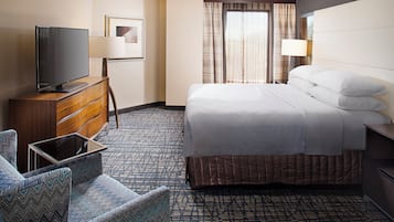 A hotel room with a bed, a TV, a desk, and a chair.