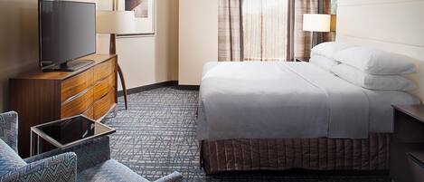 A hotel room with a bed, a TV, a desk, and a chair.