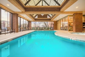 A swimming pool with a clear blue water, surrounded by lounge chairs and a glass wall. - Crowne Plaza Annapolis by IHG (Annapolis)