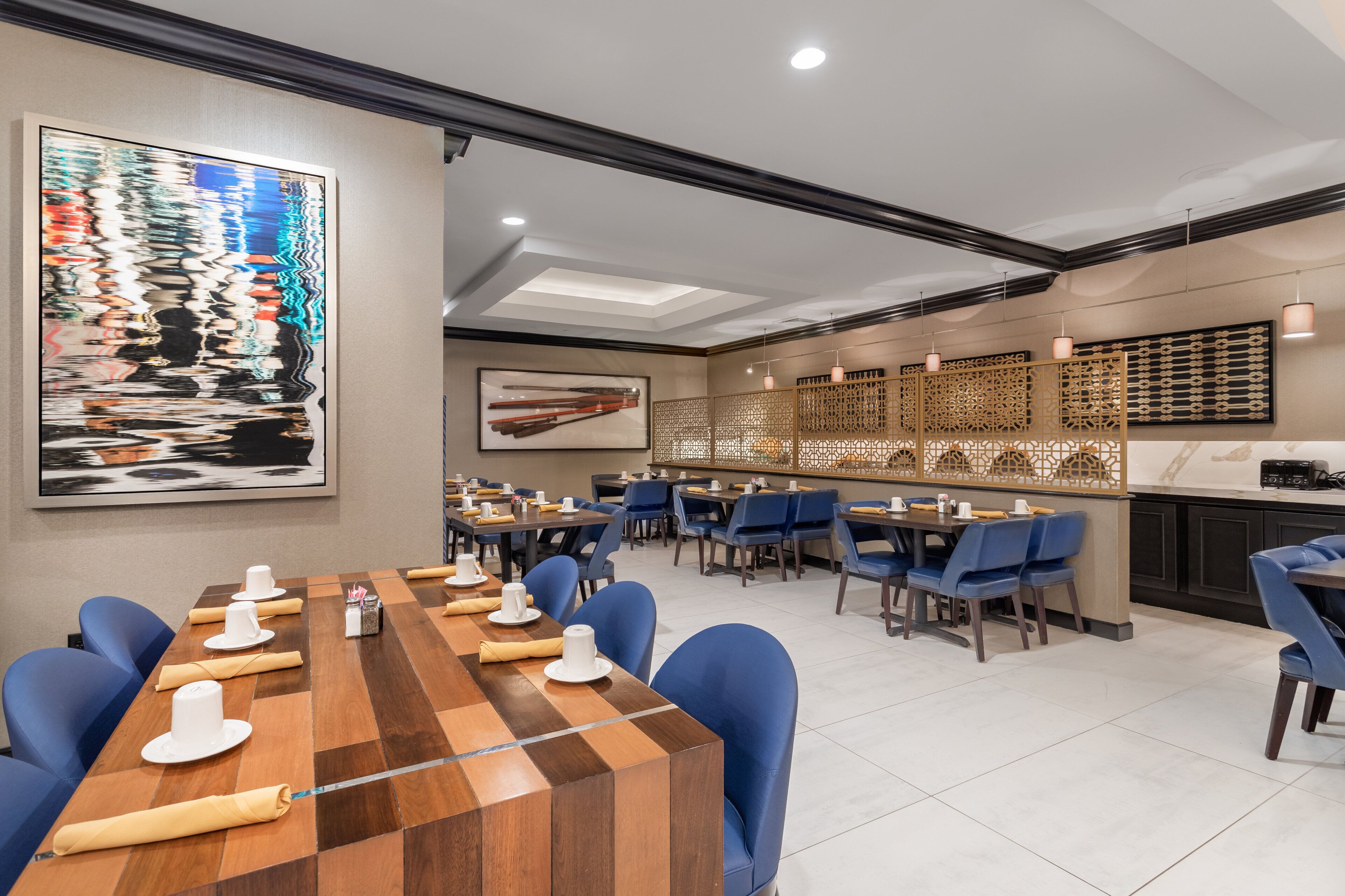 A conference room with a long table, blue chairs, and a large abstract painting on the wall.