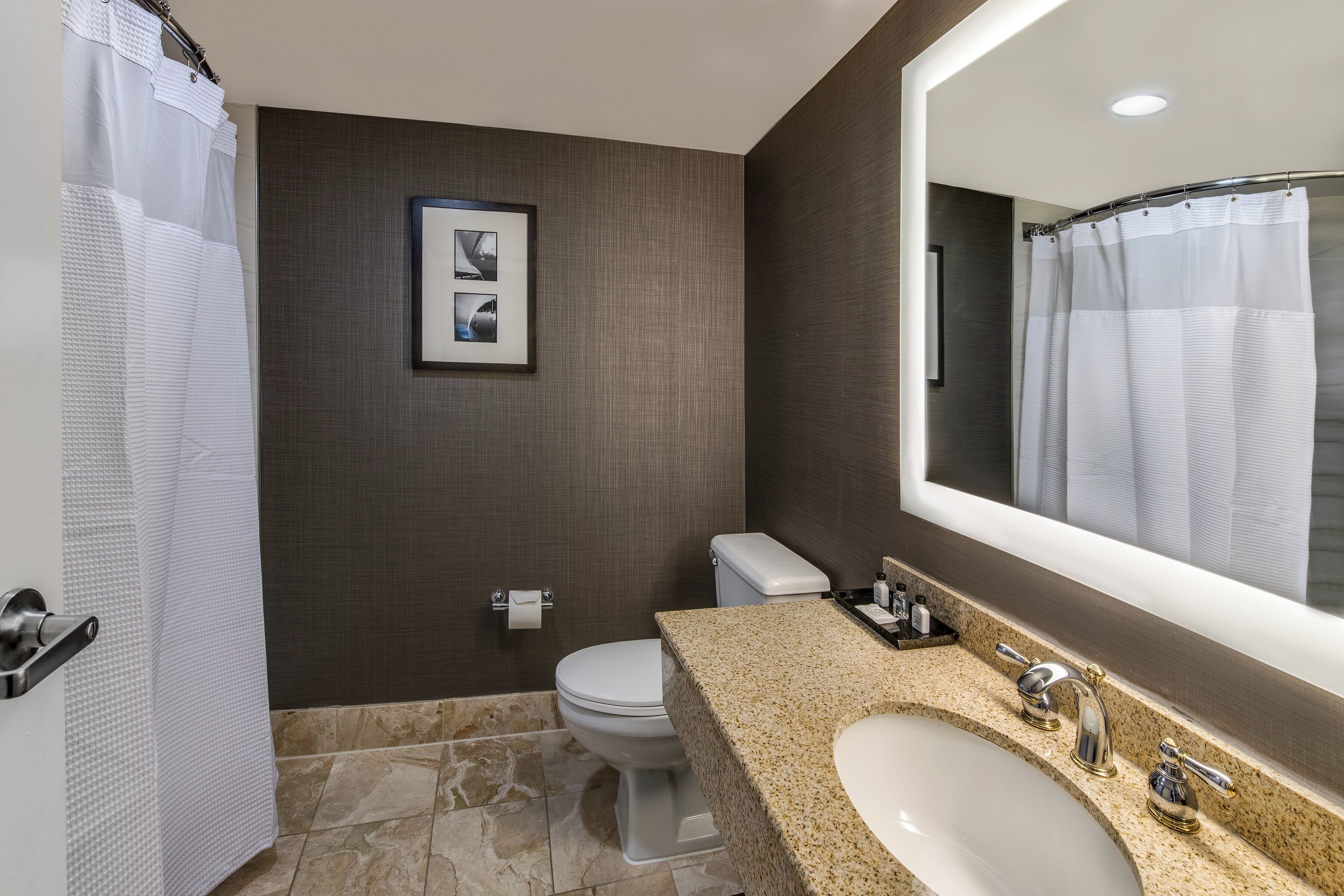 A modern bathroom with a toilet, sink, and shower curtain.