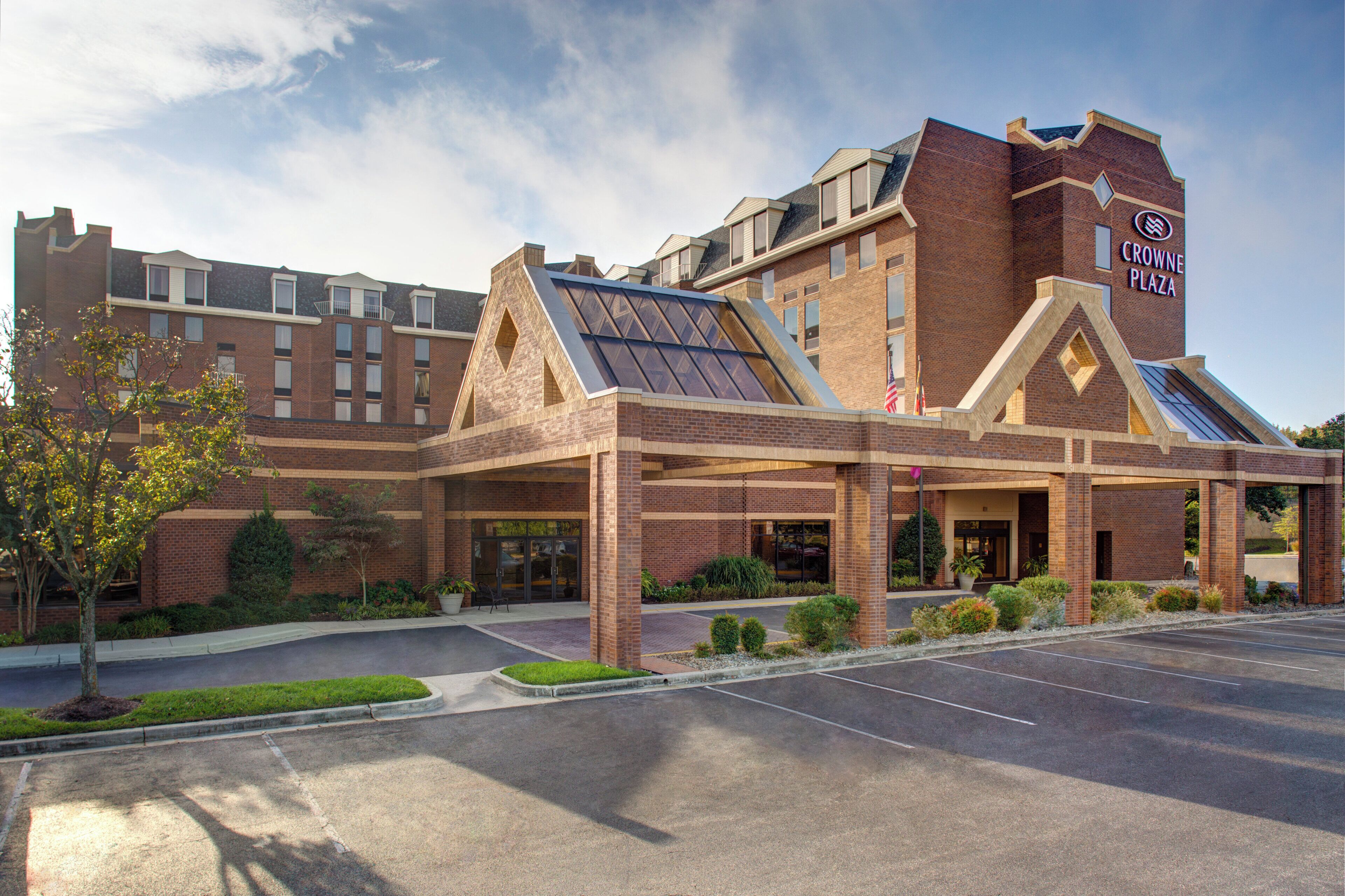 A hotel with a prominent entrance, a covered waiting area, and a parking lot.