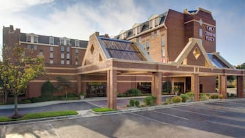 A hotel with a prominent entrance, a covered waiting area, and a parking lot.