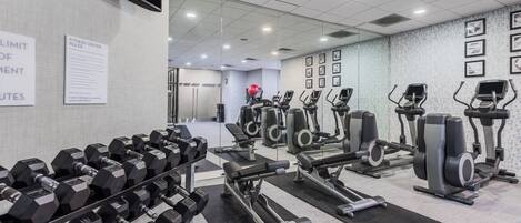 A gym with various exercise equipment, including dumbbells, treadmills, and stationary bikes.