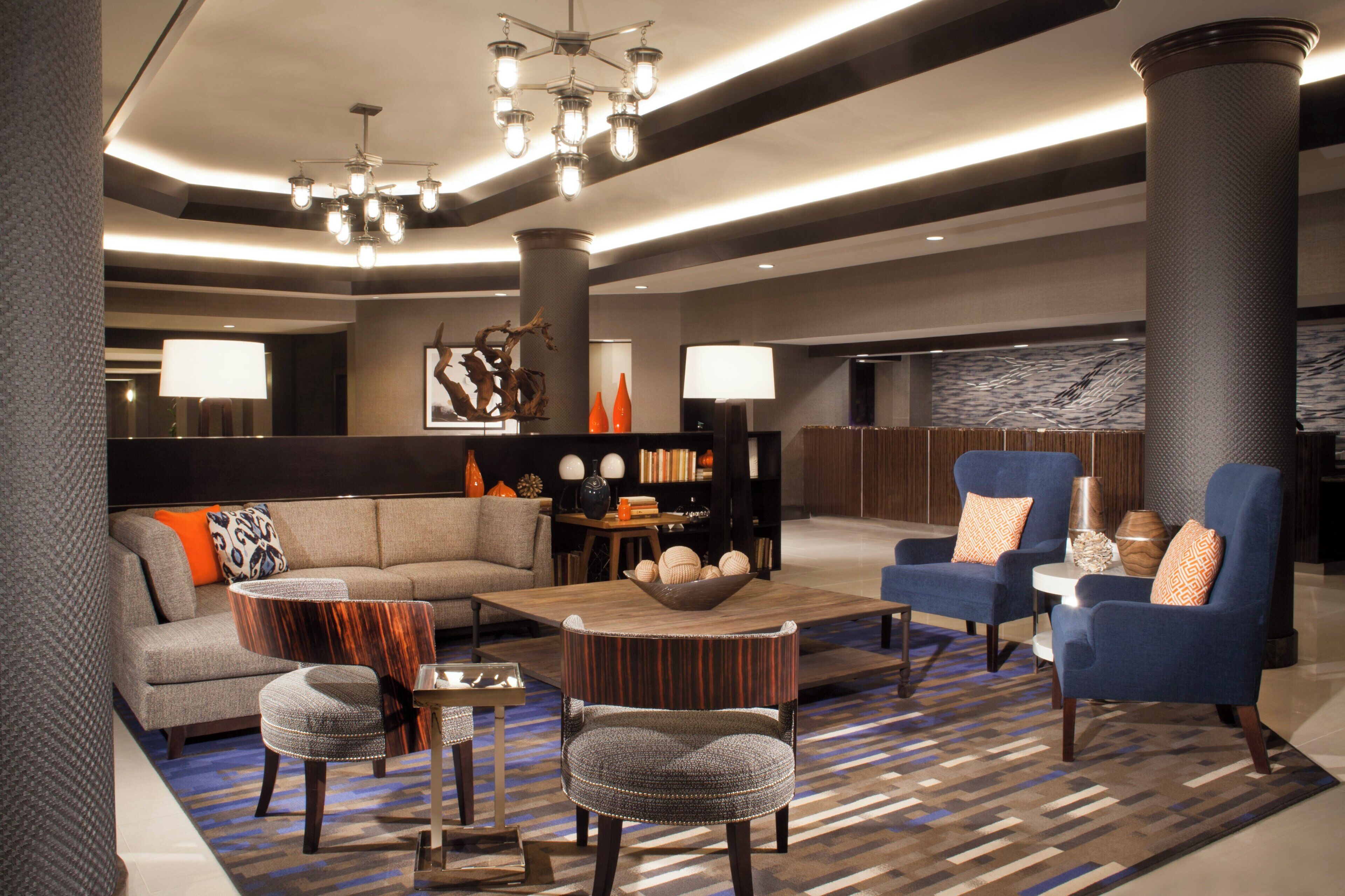 Un lobby moderno con un sofá seccional, un sillón azul y una mesa de centro.