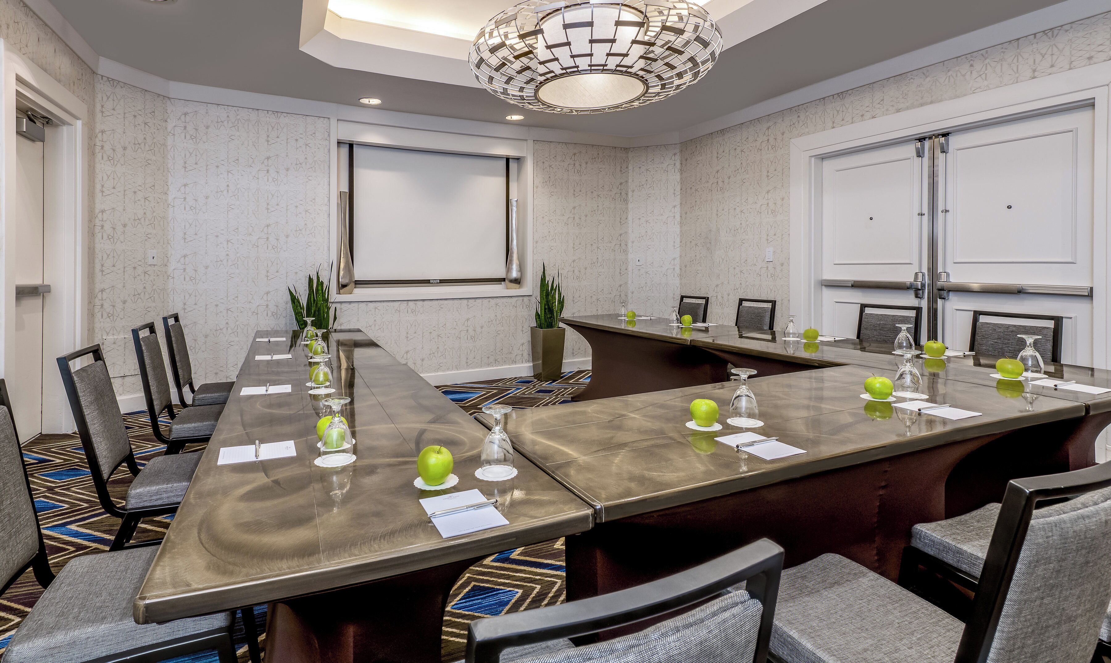 A conference room with a long table, chairs, and a modern chandelier.