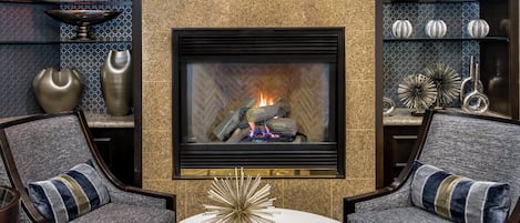 Una sala de estar moderna con chimenea, dos sillones, una mesa de centro y elementos decorativos.