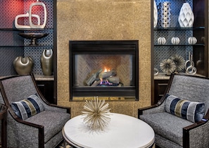 A modern living room with a fireplace, two armchairs, a coffee table, and decorative items. - Crowne Plaza Annapolis by IHG (Annapolis)
