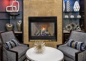 A modern living room with a fireplace, two armchairs, a coffee table, and decorative items.