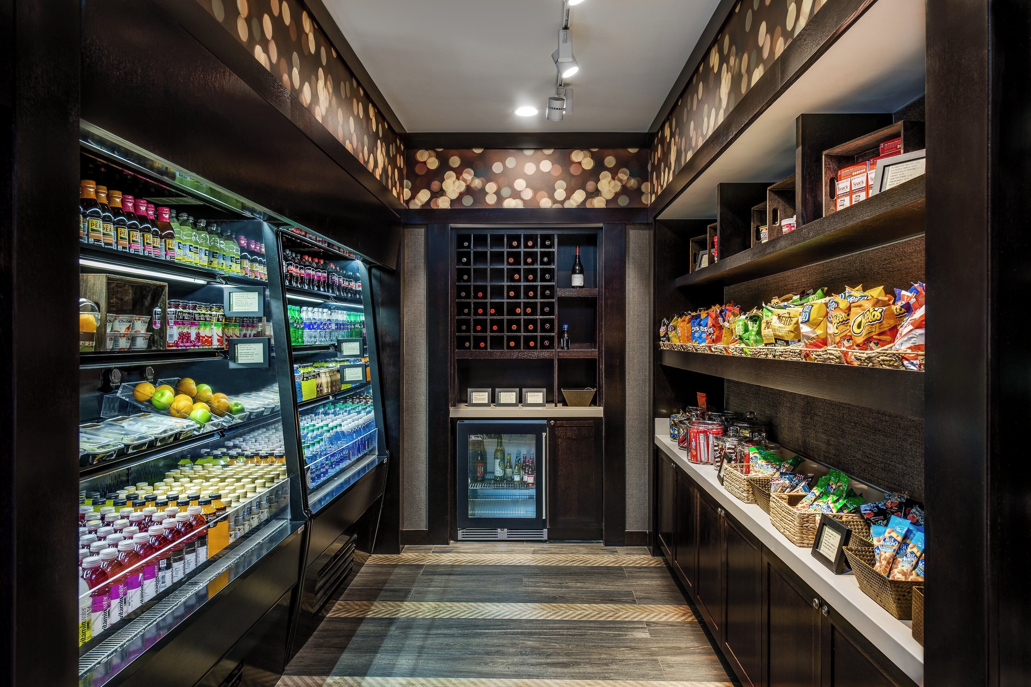 Un kiosque bien éclairé où l’on peut acheter des collations et des boissons, avec un choix varié de produits, notamment de l’eau en bouteille, des jus de fruits et des en-cas.