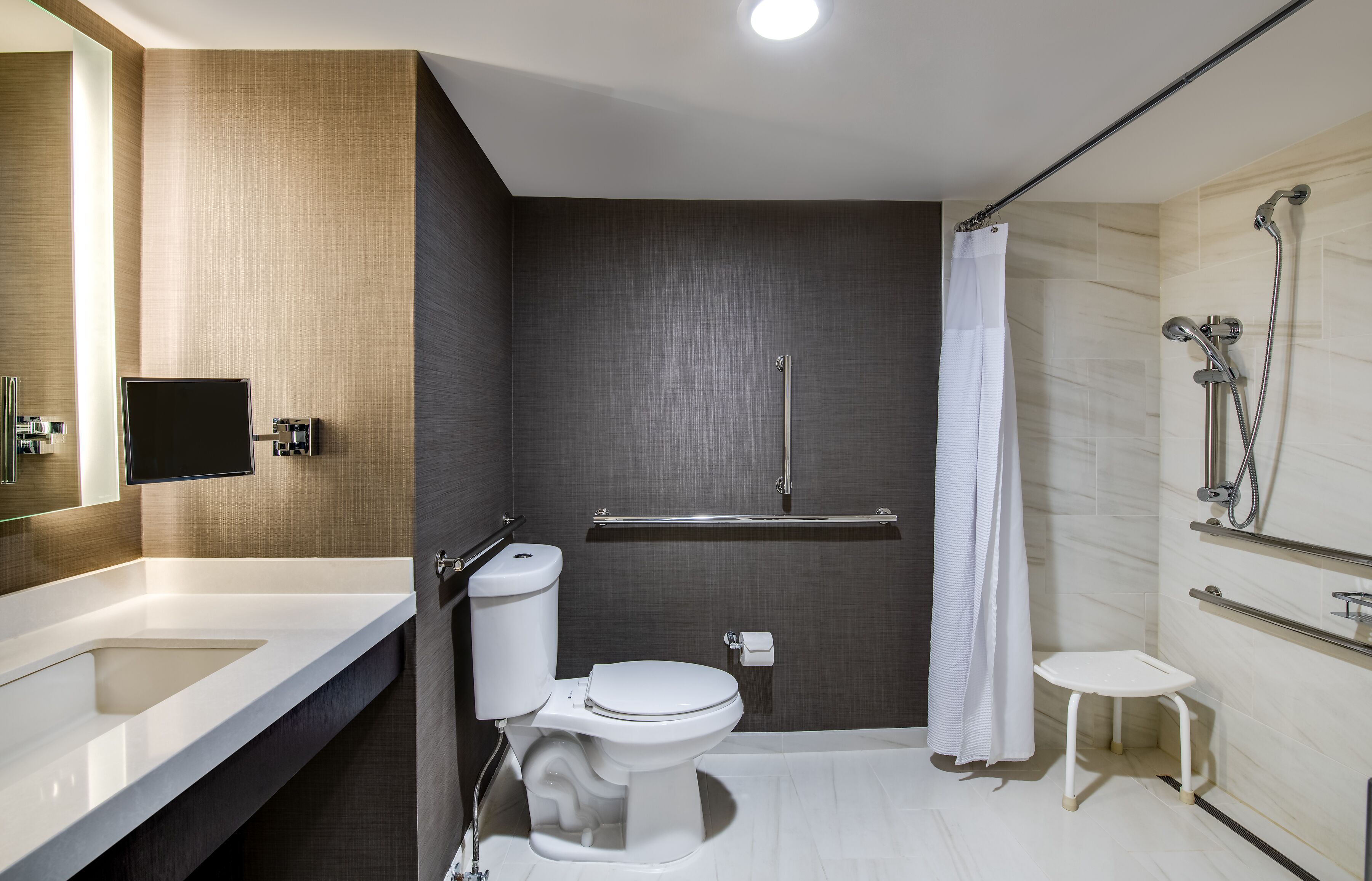 Ein modernes Badezimmer mit Toilette, Waschbecken, Dusche und einem kleinen Hocker.