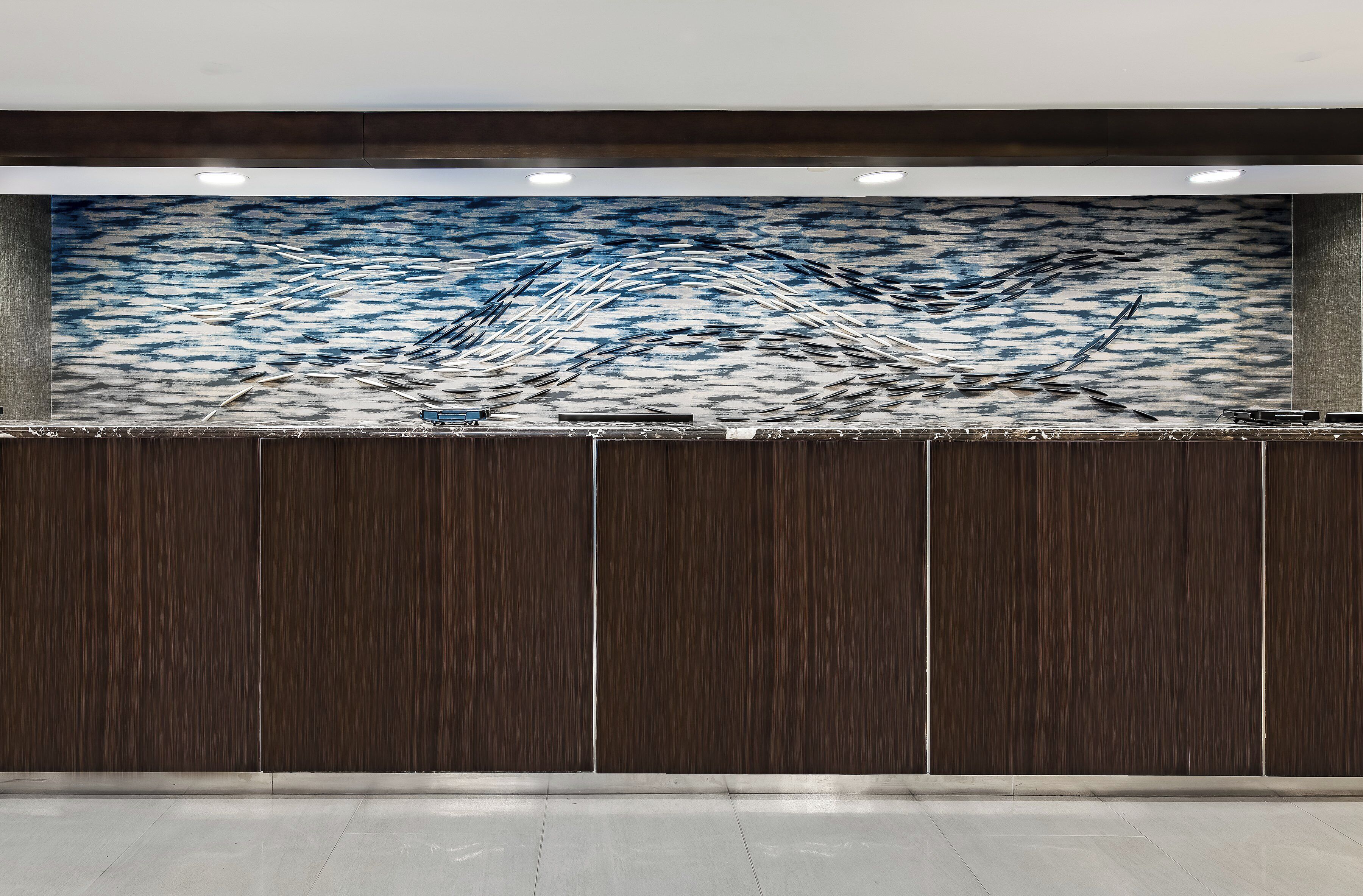 A reception desk with a large abstract mural above it.