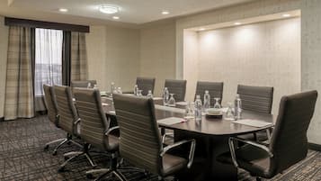 A conference room with a long table, multiple chairs, and various items like water bottles and glasses.