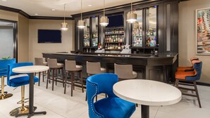 A bar area with multiple seating options, including bar stools and round tables, and a well-stocked bar counter. - Crowne Plaza Annapolis by IHG (Annapolis)