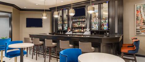 A bar area with multiple seating options, including bar stools and round tables, and a well-stocked bar counter.