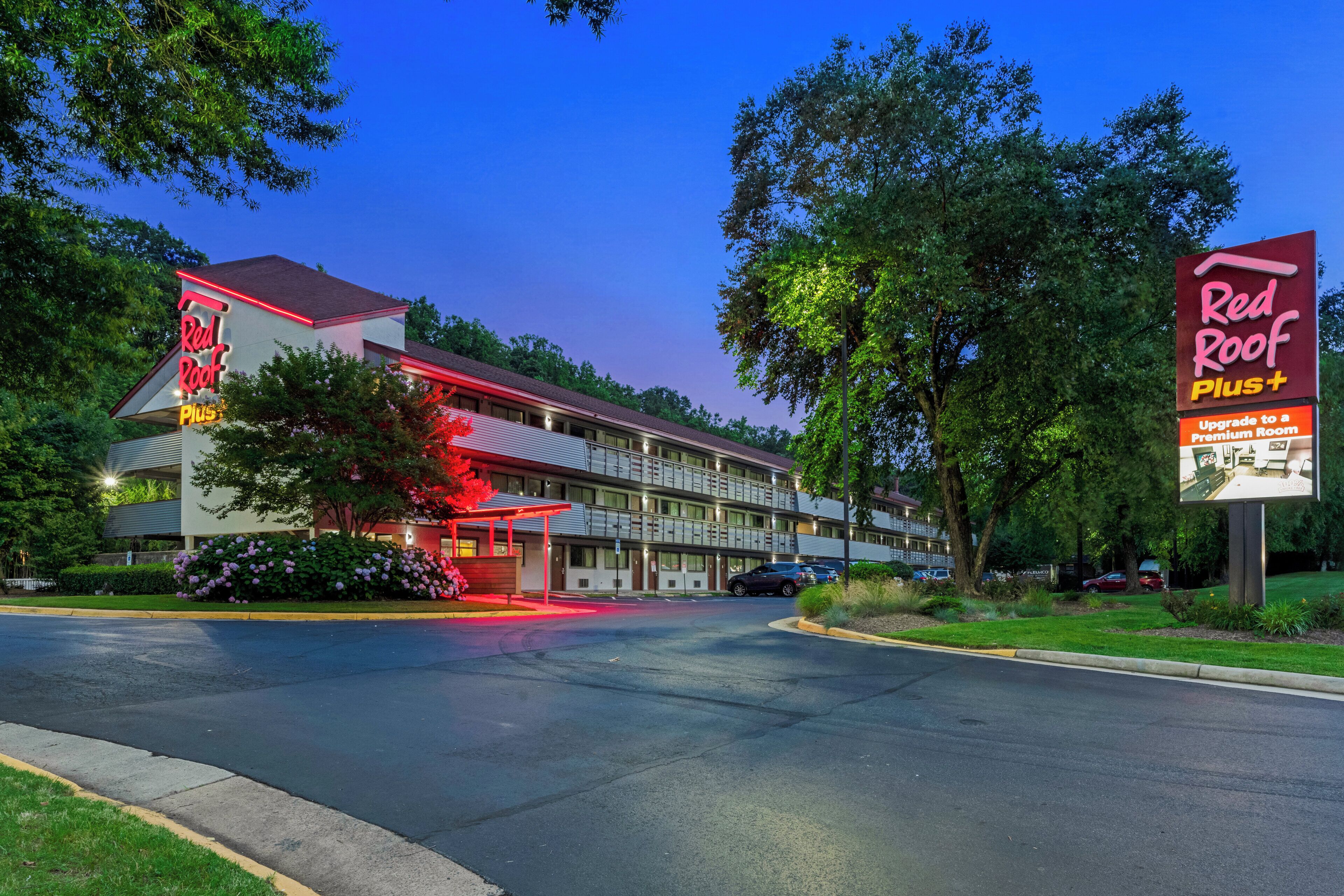 Un motel con letrero de techo rojo, varios espacios de estacionamiento y un césped bien cuidado.